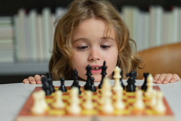 Criança brincando de xadrez Criança jogando jogo de tabuleiro Criança pensando brainstorming e ideia no jogo de xadrez Desenvolvimento infantil infantil Menino jogando xadrez em casa Retrato de perto rosto engraçado