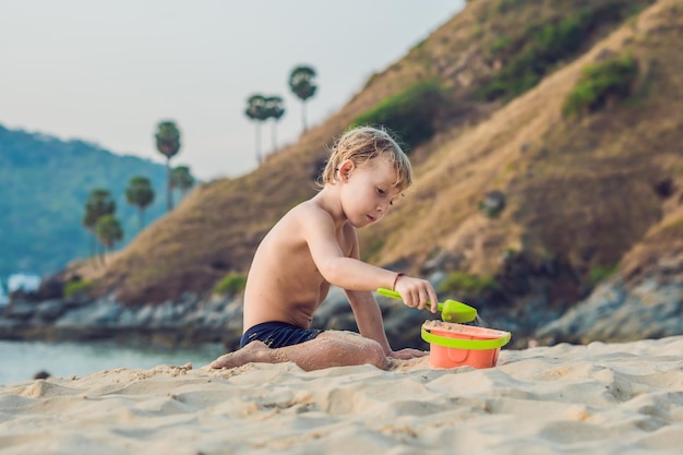 Criança brincando na praia com pá e balde