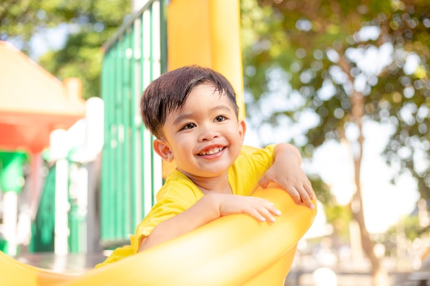 Criança brincando no playground ao ar livre. as crianças brincam no pátio da escola ou do jardim de infância. criança ativa no slide colorido e balanço. atividade de verão saudável para crianças.