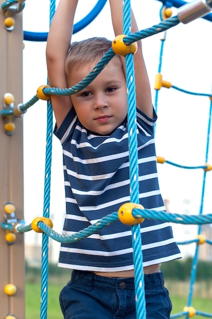 Criança brincando no playground ao ar livre. As crianças brincam no pátio da escola ou do jardim de infância.