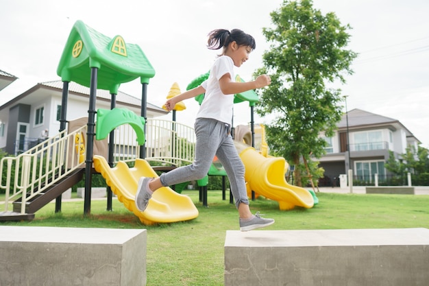 Criança brincando no playground ao ar livre. As crianças brincam no pátio da escola ou do jardim de infância.