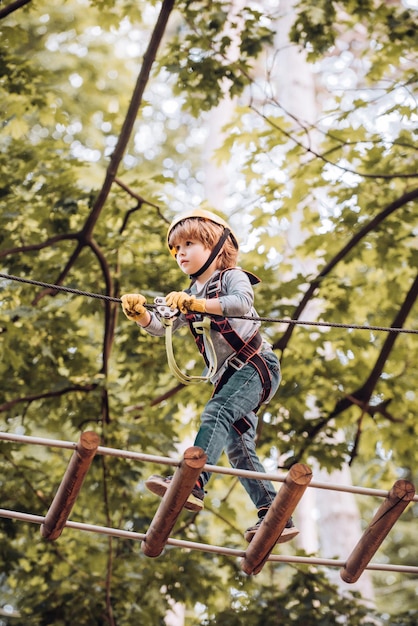 Criança brincando no recreio, menino de escola bonito, desfrutando de um dia ensolarado em uma aventura de escalada