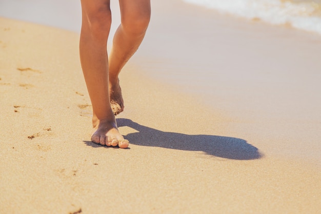 Criança caminha ao longo da praia deixando pegadas na areia