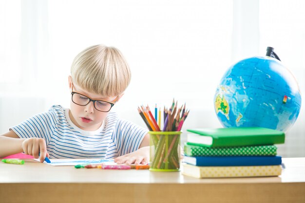 Criança cansada de aprender. aluno infeliz. garotinho exausto. rapaz na sala de aula. garoto fazendo lição de casa.