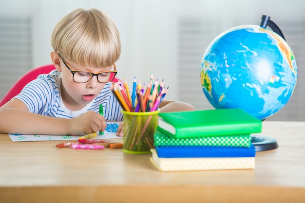 Criança cansada de aprender. aluno infeliz. garotinho exausto. rapaz na sala de aula. garoto fazendo lição de casa.