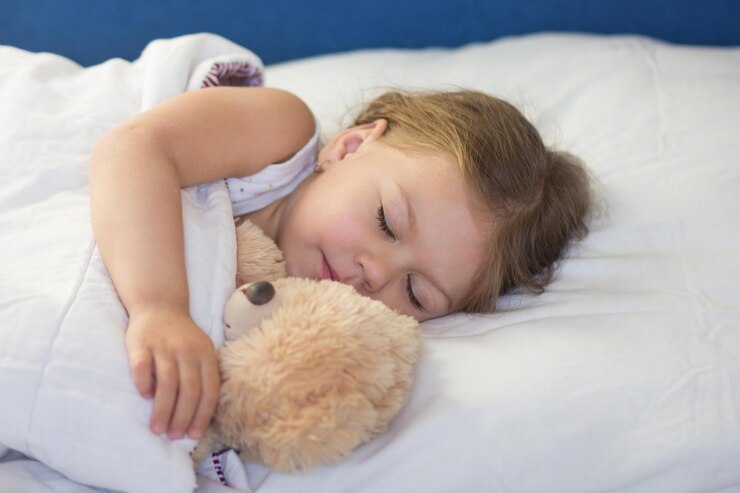 Foto criança caucasiana de três anos dormindo na cama com brinquedo de urso durante o dia