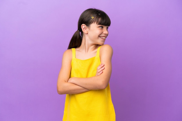 Criança caucasiana isolada em fundo roxo com braços cruzados e feliz