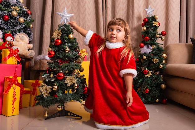 Criança caucasiana organizar decorar árvore de Natal com conceito de ideias festivas de Natal divertidas e alegres