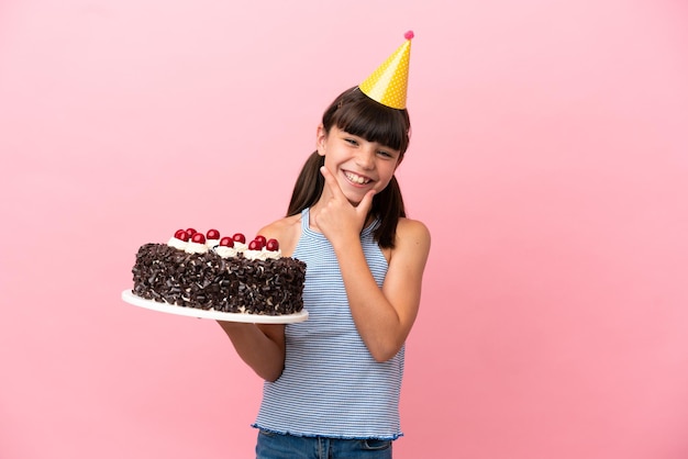 Criança caucasiana segurando bolo de aniversário isolado em fundo rosa feliz e sorridente