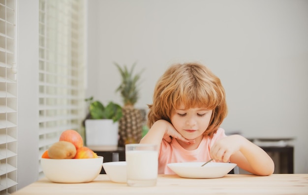 Criança caucasiano menino comendo sopa saudável na cozinha nutrição infantil