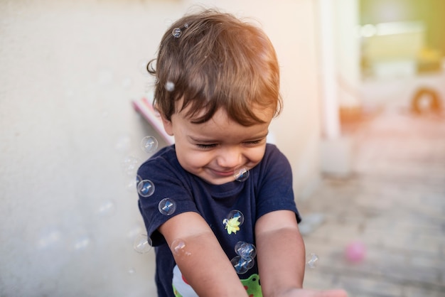 Foto criança com camiseta azul brincando com bolhas de sabão