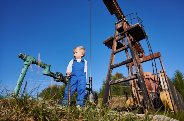 Foto criança com capacete de pé no território de um poço de petróleo