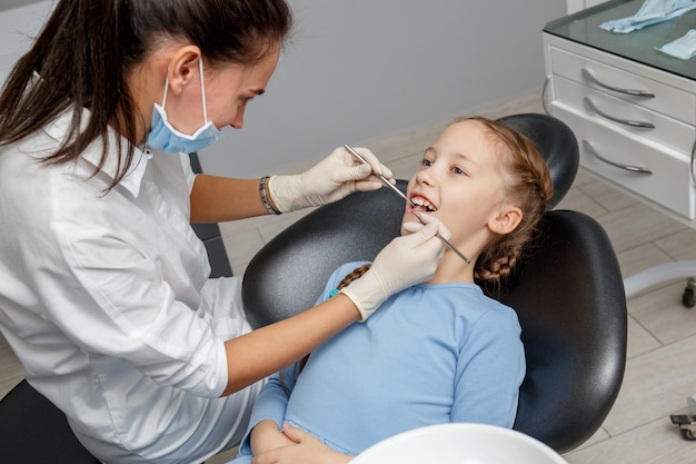 Criança com check-up odontológico por especialista em consultório dentário