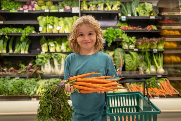 Criança com criança de cenoura em compras na mercearia do supermercado escolhendo mercadorias para compras saudáveis