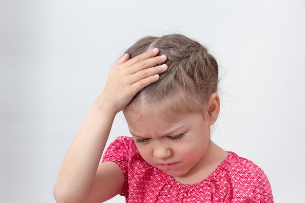 Criança com dor de cabeça segurando a mão na cabeça sobre fundo branco menina caucasiana de 5 6 anos