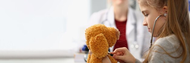 Criança com estetoscópio escuta brinquedo no fundo senta-se médico