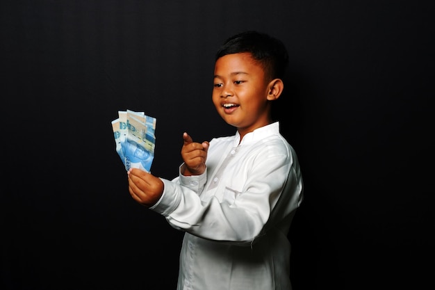 Criança com expressão feliz enquanto segura muito dinheiro isolado em fundo preto