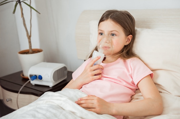 Criança com fibrose cística deitada em uma cama com máscara de nebulizador