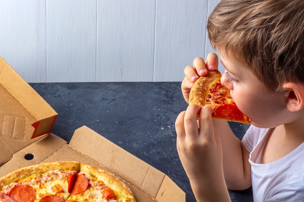 Criança com fome come apetite de pepperoni pizza em casa. fechar-se. almoço ou jantar tradicional italiano. lanche infantil