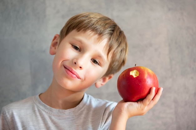 Criança com frutas Menino engraçado com maçãs lindas mordidas