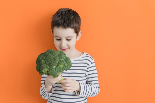 Criança com fundo laranja de brócolis vegetal