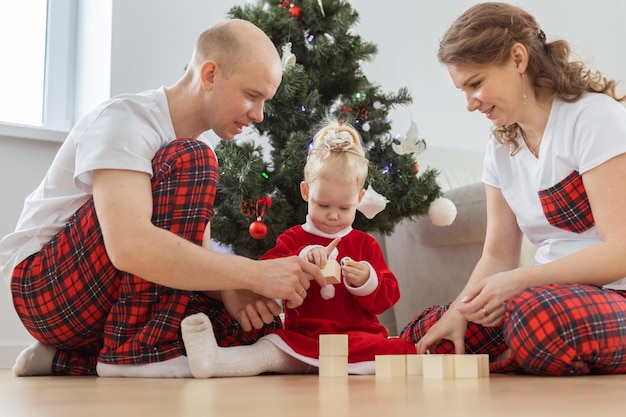 Criança com implante coclear brinca com os pais sob a surdez da árvore de natal e tecnologias médicas inovadoras para aparelhos auditivos