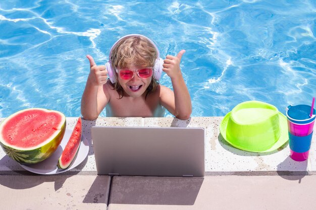 Criança com laptop na piscina em um dia de verão Trabalho fora do conceito Negócios e verão