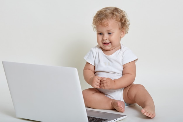 Criança com laptop sentado no chão e olhando os desenhos no caderno