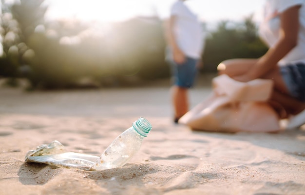 Criança com mãe coleta lixo plástico na praia à beira-mar Garrafas plásticas sujas usadas vazias