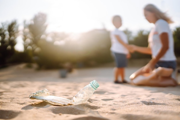 Criança com mãe coleta lixo plástico na praia à beira-mar Garrafas plásticas sujas usadas vazias