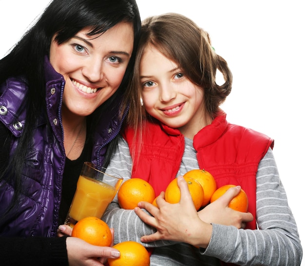 Criança com mãe segurando laranjas e suco