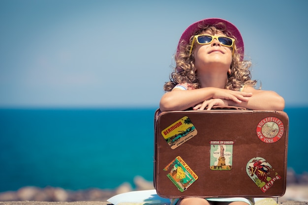 Criança com mala vintage nas férias de verão. conceito de viagem e aventura