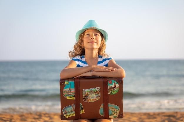 Criança com mala vintage nas férias de verão