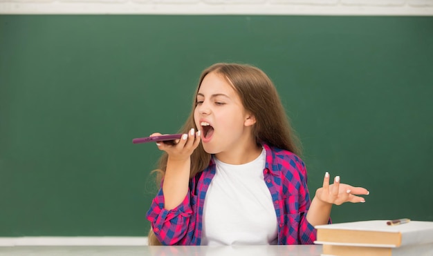 Criança com raiva na escola falando ao telefone no fundo do quadro-negro telefonema