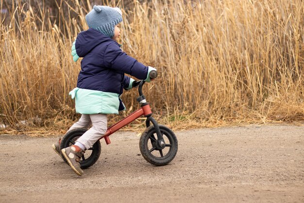 criança com roupas azuis se divertindo andando de bicicleta na estrada nos subúrbios