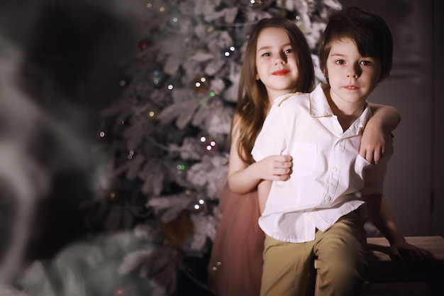 Criança com roupas elegantes na frente da árvore de Natal. Véspera de Ano Novo. Esperando pelo novo ano.