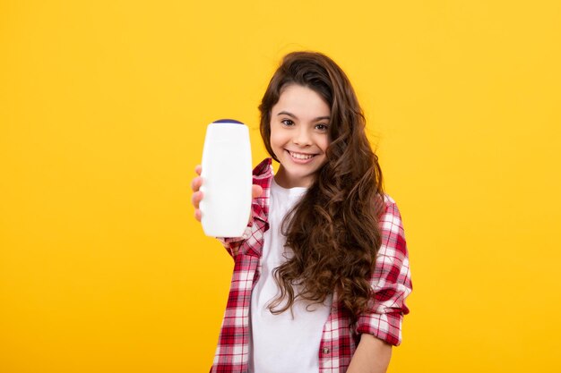 Foto criança com shampoo condicionador cuidado cosmético diário adolescente segurar garrafa de cabelo e cuidados com a pele