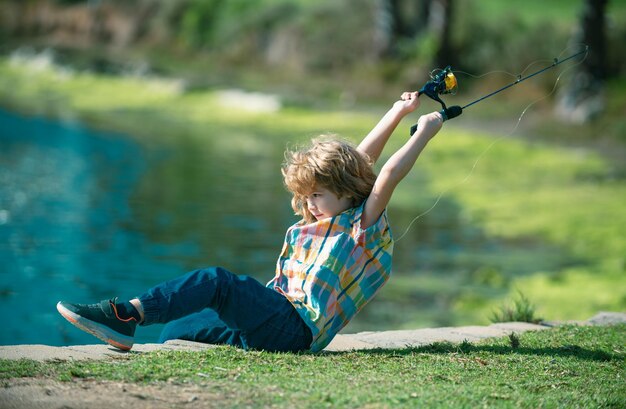 Foto criança com spinner no rio retrato de menino animado pescando menino no cais com conceito de pesca de vara