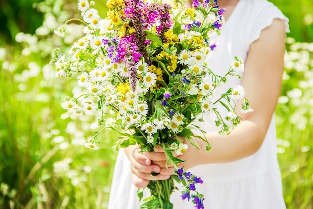 Criança com um buquê de flores silvestres. foco seletivo. natureza.