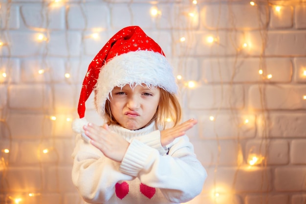 Criança com um chapéu vermelho de Natal mostrando gestos de recusa