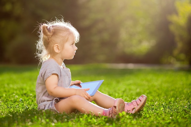 Criança com um tablet sentada no parque