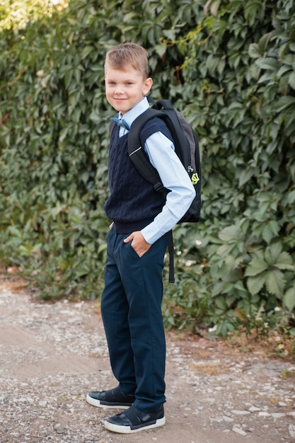 Criança com uniforme escolar e mochila vai para a escola no contexto de uma trepadeira