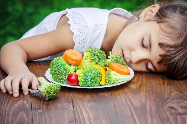 Criança come legumes. Foto de verão. Foco seletivo.