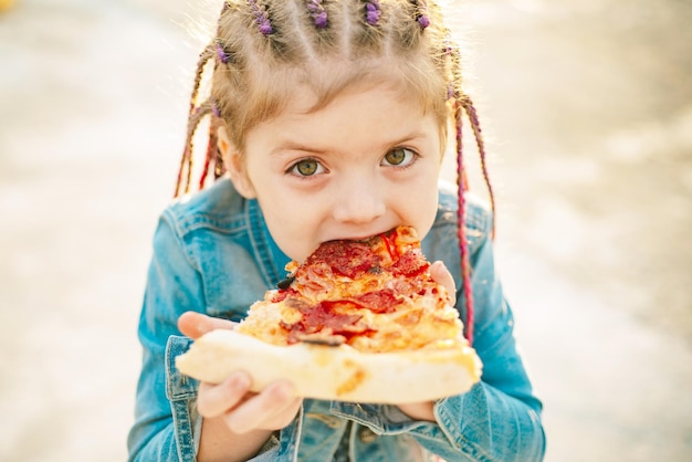 Criança come pizza. Criança comendo pizza. Fastfood para crianças. Junkfood italiano. Comida favorita das crianças.