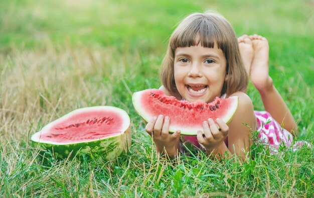 Criança come uma melancia no jardim