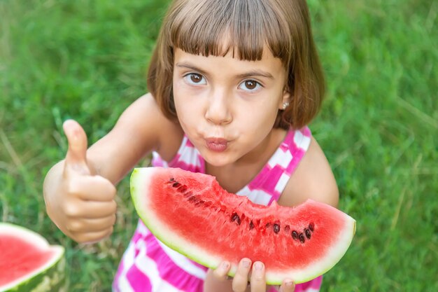 Criança come uma melancia no jardim