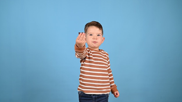 Criança comendo doces em um fundo azul. Foto de alta qualidade