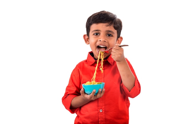 Criança comendo macarrão delicioso, criança indiana comendo macarrão com garfo em branco