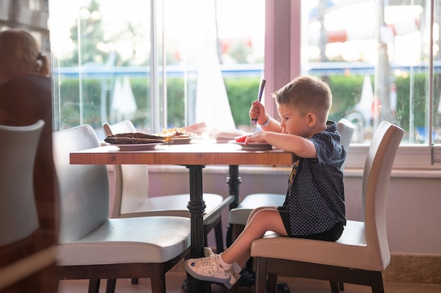 Criança comendo melancia em um restaurante.