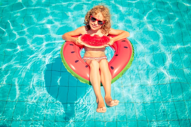 criança comendo melancia em uma melancia inflável na piscina